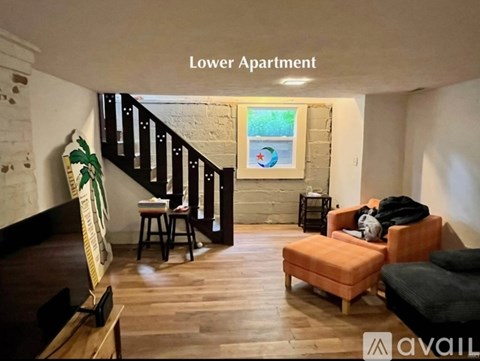 A living room with a staircase and a painting on the wall.
