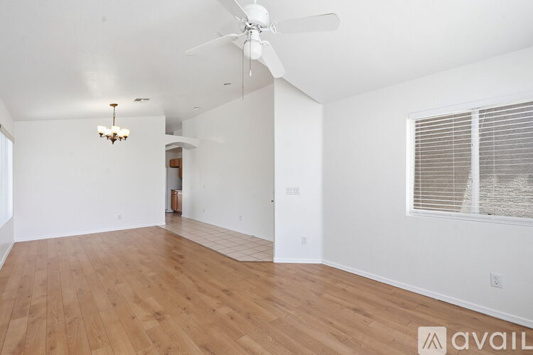 A spacious room with wooden flooring and a ceiling fan.
