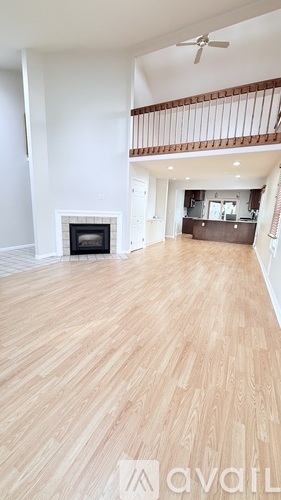 A spacious room with wooden flooring and a fireplace.
