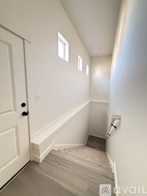 A staircase with a white door on the left and a window on the wall.