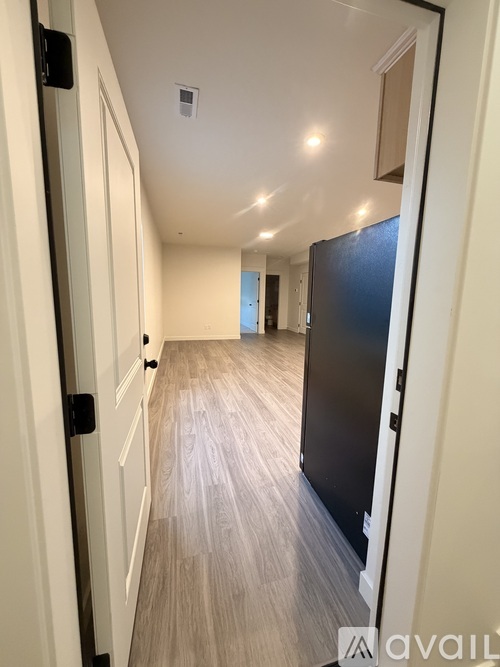 A long hallway with a black door on the right.