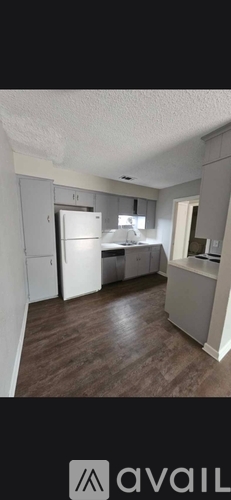 A kitchen with a refrigerator, sink, and cabinets.