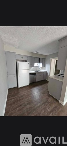 A kitchen with a refrigerator, sink, and cabinets.