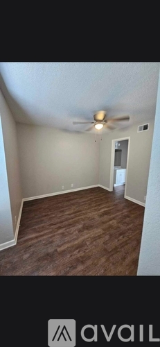 A room with a ceiling fan and wooden flooring.