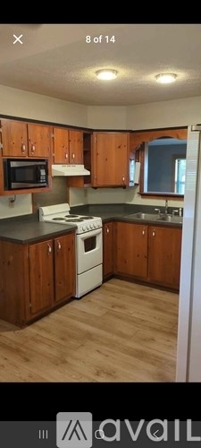 A kitchen with wooden cabinets and a white stove top oven.