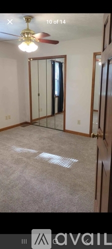 A room with a ceiling fan and a mirror on the wall.