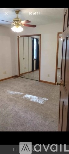 A room with a ceiling fan and a mirror on the wall.