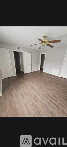 A room with a ceiling fan and wooden flooring.