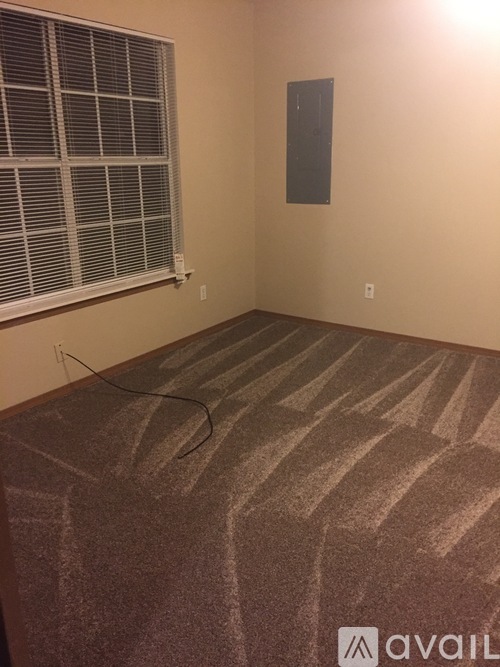 A room with a carpeted floor and a window with blinds.