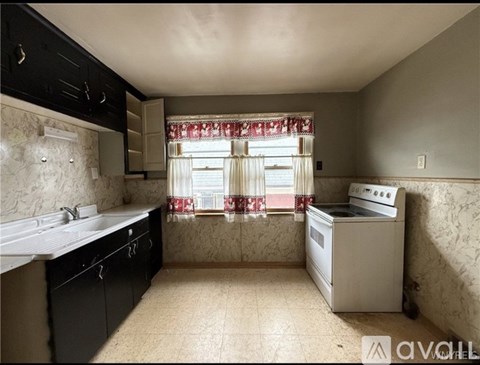 A kitchen with black cabinets and a white sink.