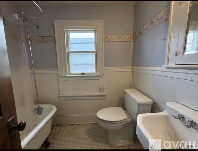 A white toilet sits next to a bathtub in a bathroom.