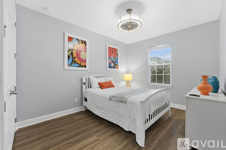 A bedroom with a white bed and two paintings on the wall.