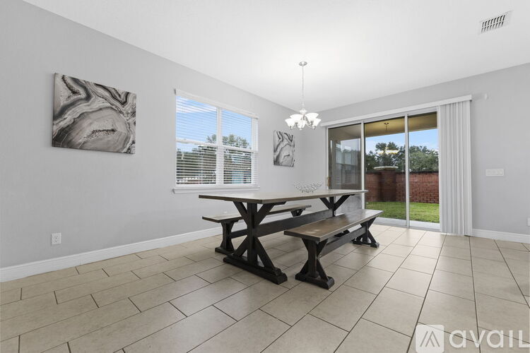 A dining room with a table and chairs and a painting on the wall.
