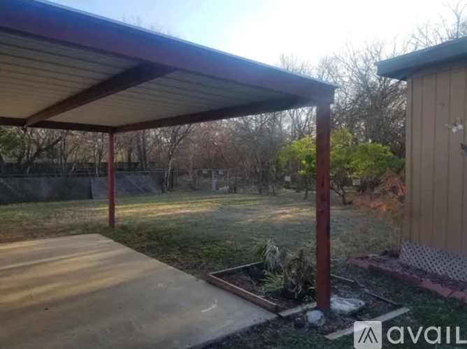 A covered patio area with a wooden deck and a metal roof.