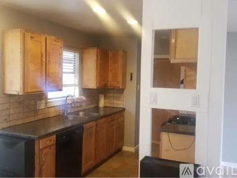 A kitchen with wooden cabinets and a black dishwasher.