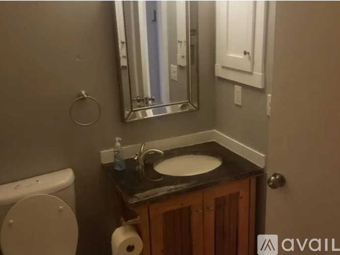 A bathroom with a toilet, sink, mirror, and towel rack.