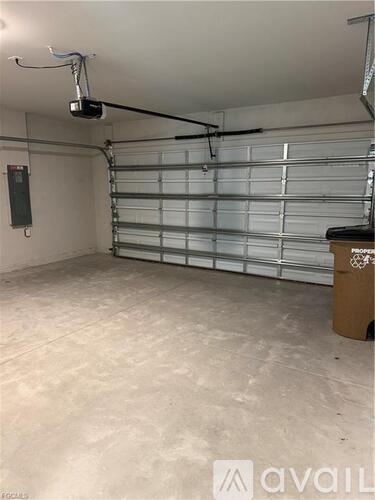A spacious garage with a closed white door and a black speaker hanging from the ceiling.
