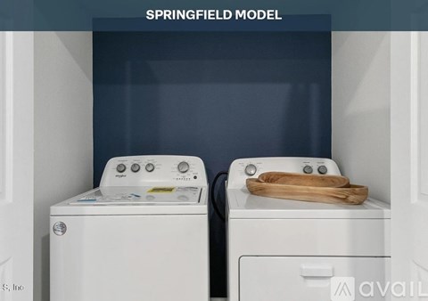 Two white washing machines are in a Springfield model laundry room.