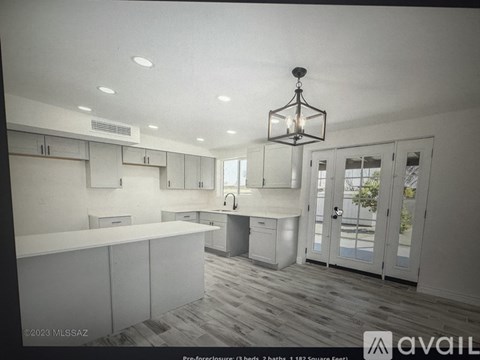 A modern kitchen with white cabinets and a wooden floor.