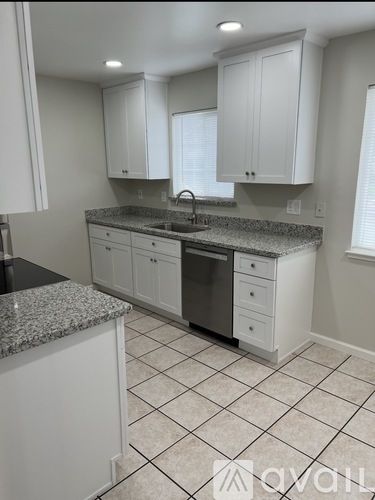 A kitchen with white cabinets and a granite countertop.