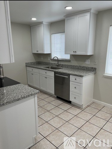 A kitchen with white cabinets and a granite countertop.