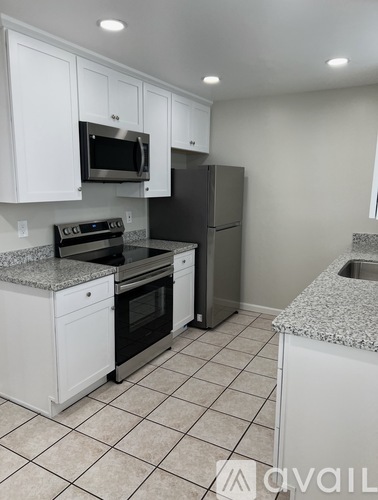 A kitchen with white cabinets and a granite countertop.