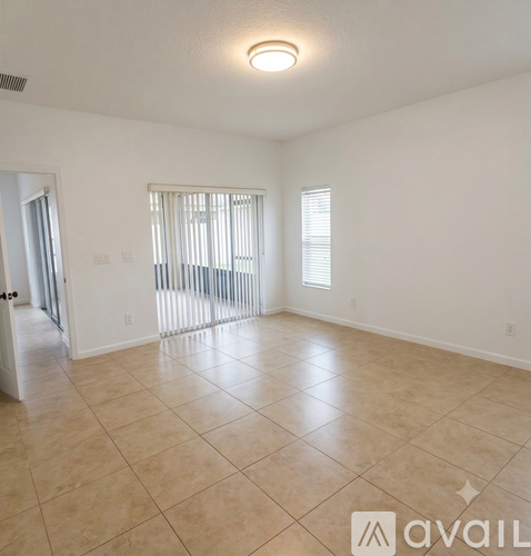 A spacious room with tiled flooring and a window with blinds.