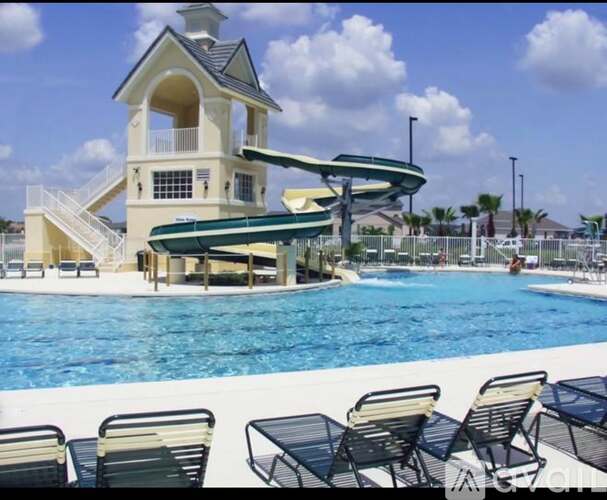 A pool with a slide and a building next to it.