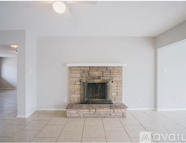 A living room with a stone fireplace and tiled floor.