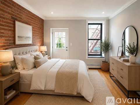 A bedroom with a large bed, a nightstand with a lamp, and a mirror on the dresser.
