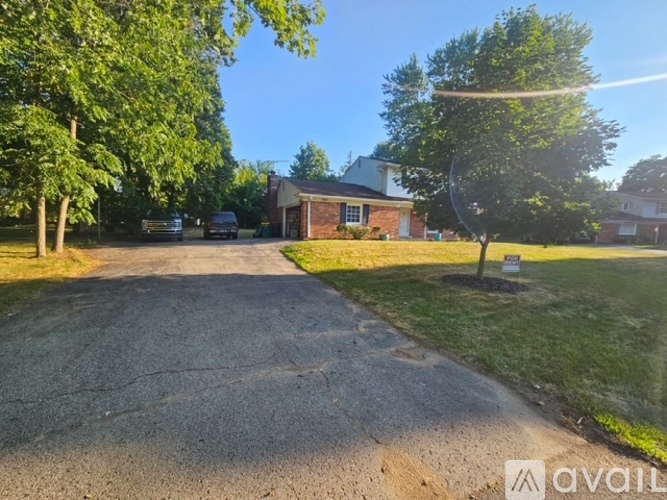 A house with a driveway and trees in front of it.