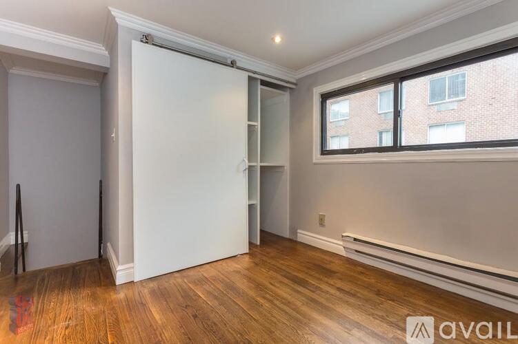 A room with a white door and a window with a view of a brick building outside.