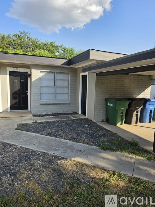A small house with a black door and a green trash can outside.