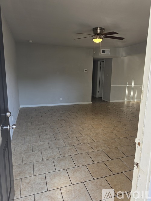 A room with a ceiling fan and tile flooring.