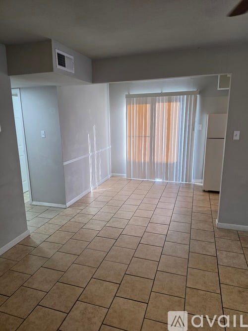 A room with tiled flooring and a window with curtains.