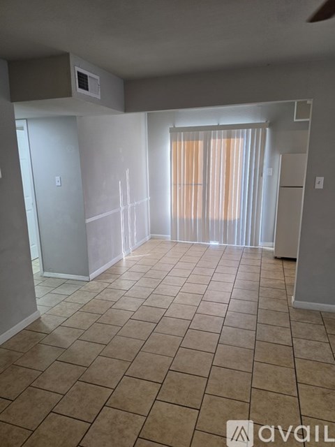 A room with tiled flooring and a window with curtains.