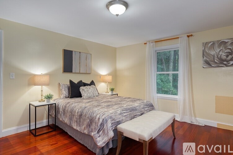 A bedroom with a bed, two lamps, and a window.
