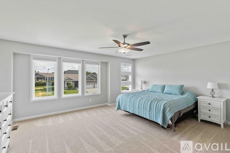 A bedroom with a bed, dresser, and a ceiling fan.