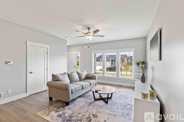 A living room with a grey couch and a ceiling fan.