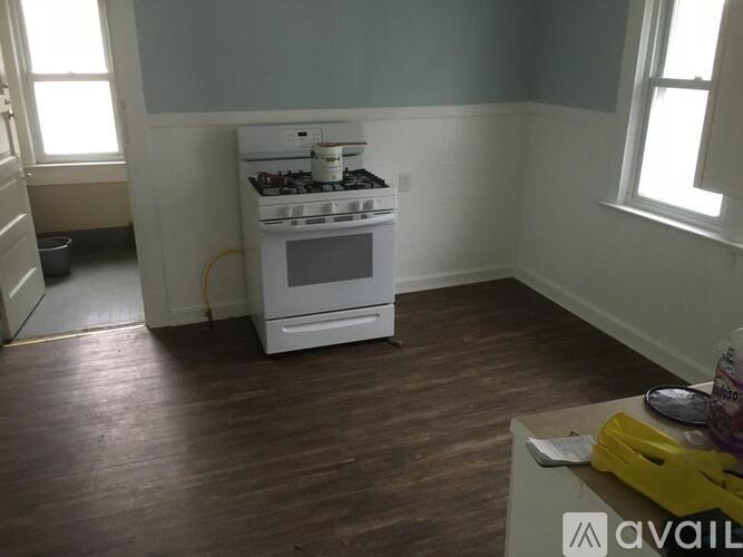 A white stove is in a kitchen with wood floors and white walls.