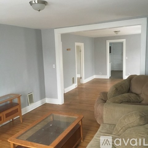 A living room with a brown couch and a glass coffee table.