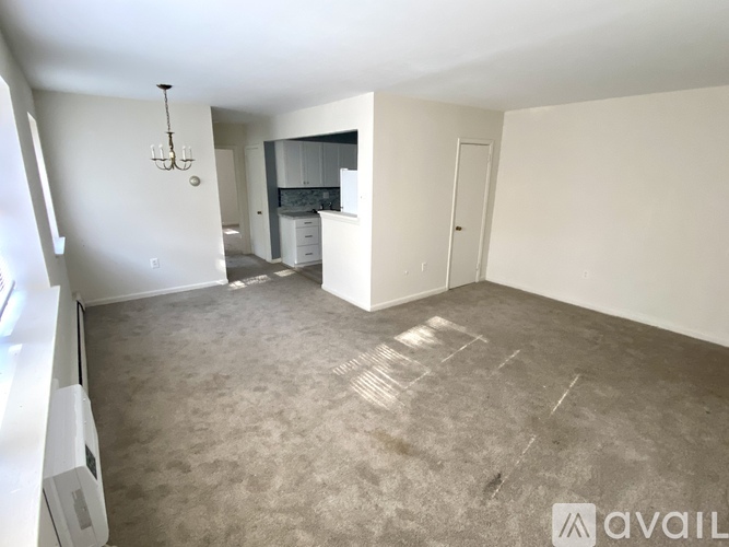 A spacious living area with a grey carpet and white walls.
