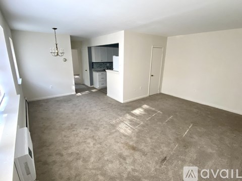 A spacious living area with a grey carpet and white walls.