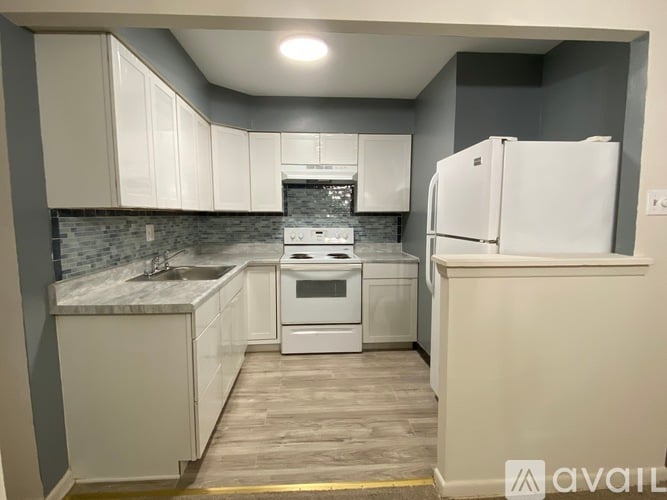 A kitchen with white cabinets and a white refrigerator.