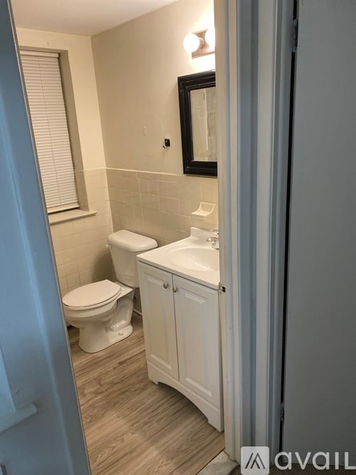 A bathroom with a toilet, sink, and cabinet.