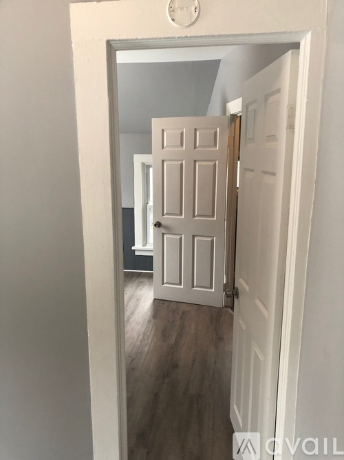 A white door with a silver handle is open.