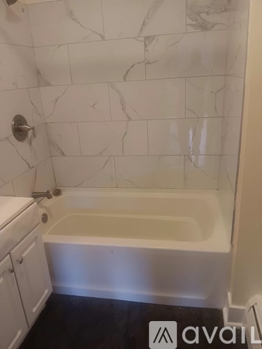 A bathroom with a marble wall and a bathtub.