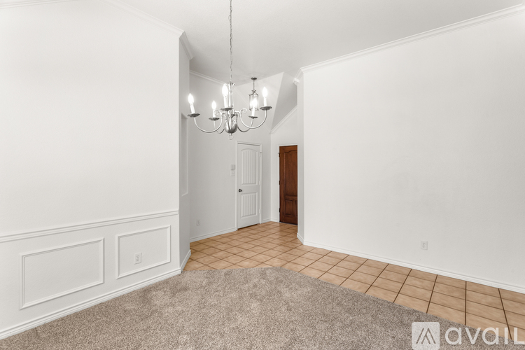 A room with a carpeted floor and a chandelier hanging from the ceiling.