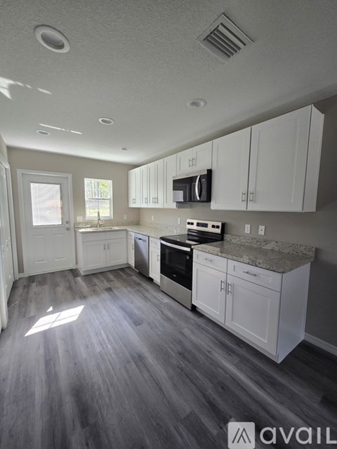 A kitchen with white cabinets and a granite countertop.