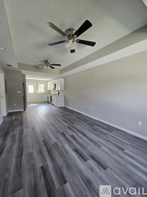 A spacious room with a ceiling fan and grey flooring.